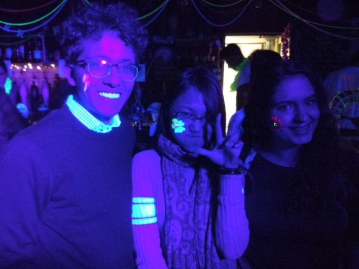 Students under neon lights smiling at the camera