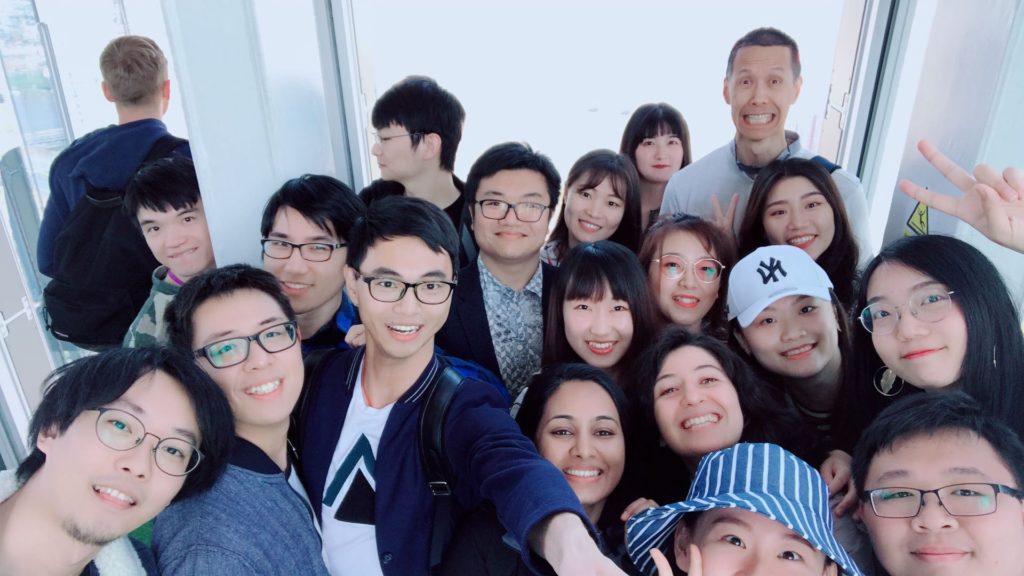 Students smiling at the camera with their tutor on the top of the Shard, London