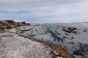 The view of a waterfall from a snowy cliff