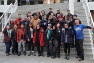 A group of people from diverse races posing happily in front of the camera.