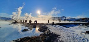 People hiking along a glacier path surrounded by thermal spa.