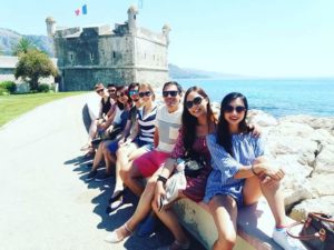 Students sitting on a wall by a beach