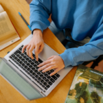 A photo of someone typing on a laptop with textbooks on either side