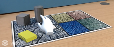 Example of AR prompt. Three objects stand on a board with five different regions. A white cartoon hand floats above one of the objects, which is highlighted in yellow. 