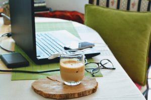 picture of a laptop and a cup of coffee at a desk at home