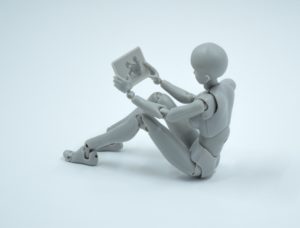 A white robot reading a laptop