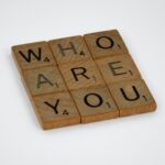 Scrabble tiles arranged in a square to read "WHO ARE YOU"