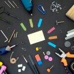 An assortment of tools and accessories arranged on a table and photographed top down, including Post-It notes, a screwdriver and pliers.