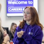 A photograph of Maddie talking to a student in the Careers Centre