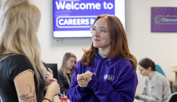A photograph of Maddie talking to a student in the Careers Centre