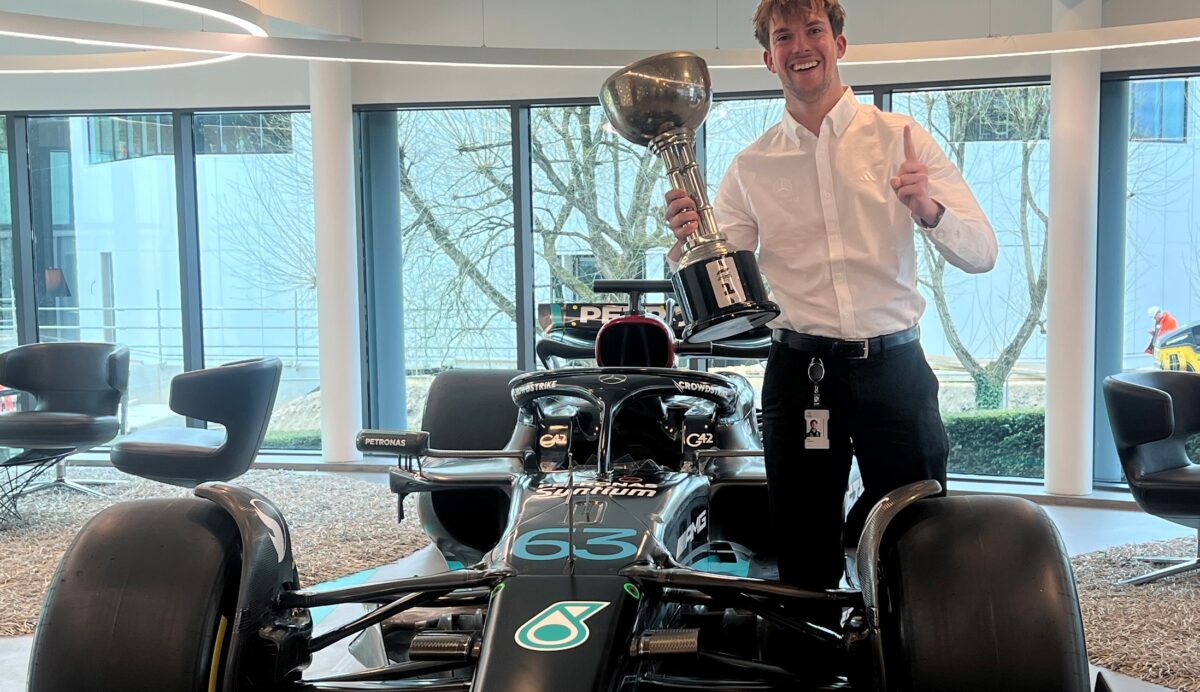 A photo of Sam Snudden standing next to an F1 car