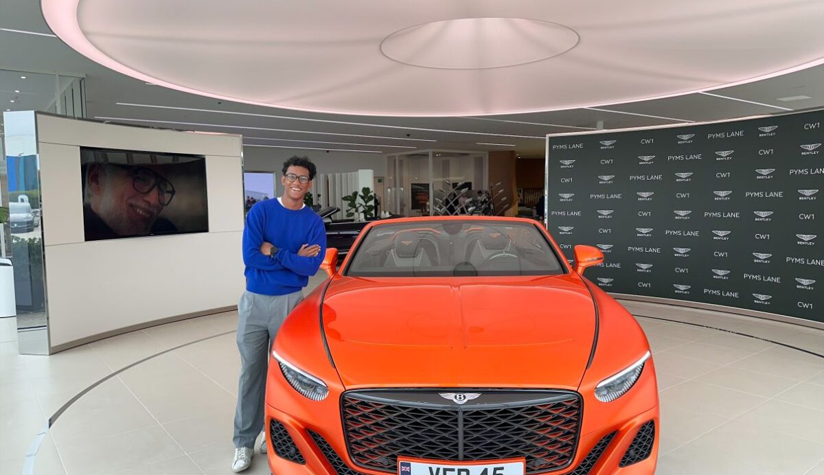A photograph of Shyan Shah standing next to an orange Bentley