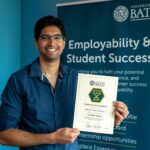 A photo of Meghan Khasnis with his Bath Award certificate
