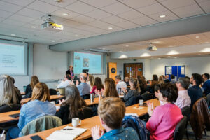 Edufest Conference, speaker at front with back of attendees sat down in audience