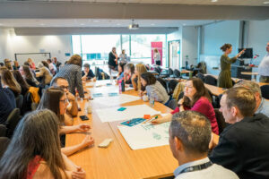 Conference attendees around a table writing notes