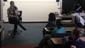 Women facing a room of students on desks