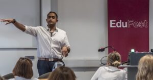 Colleague at front of room presenting with Edufest banner next to him