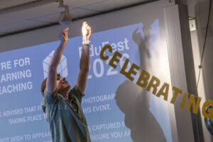 Gold celebrating banner being put up by male colleague