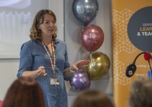 Colleague talking to room, balloons behind