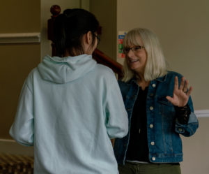 An academic in a denim jacket talks to a doctoral student.