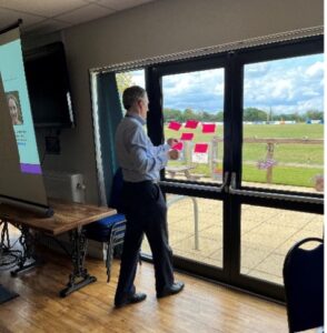 Man standing by windows with a group of pink post it notes in front of him