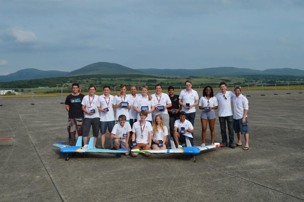 Students from Team Bath Drones pose with their winning medals and drones on an air strip