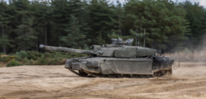 A military tank is moving rapidly cross the field.