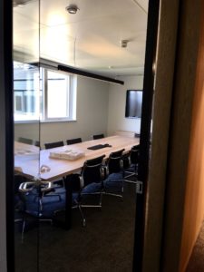 A shot of an office meeting room with chairs and a white, rectangle table.