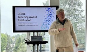 Man stood talking/presenting in front of a monitor that reads 'CEEDE Teaching Award Celebration'