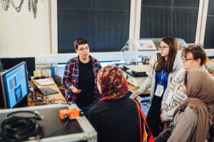 Group of 4 conference attendees on a lab tour with PhD student. 