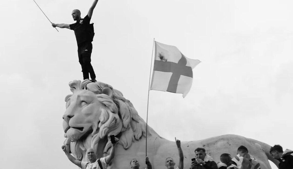 image of protestor standing on statue of lion with England flags
