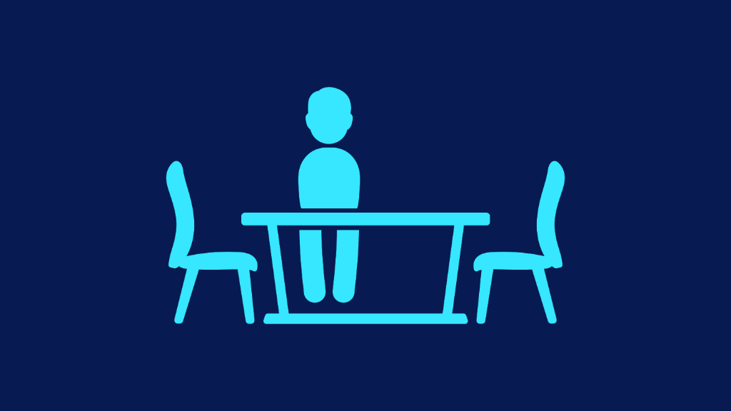 Silhouette of a person sat at an empty table.