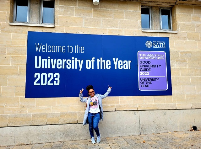 Suzan standing in front of the University of Bath's University of the Year 2023 sign