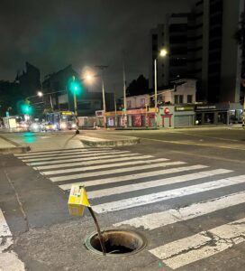 Pedestrian crossing at night with open manhole to the side