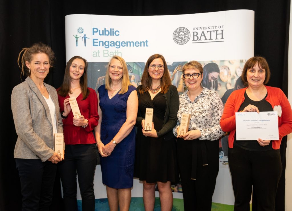 Five Vice-Chancellor's Award winners on a podium holding their awards