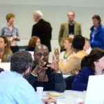 People taking part in a discussion at tables in a hall