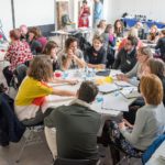 A group of people deep in discussion sat around a circular table