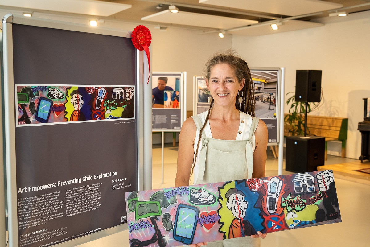 A white female stands in front of an poster in an exhibition