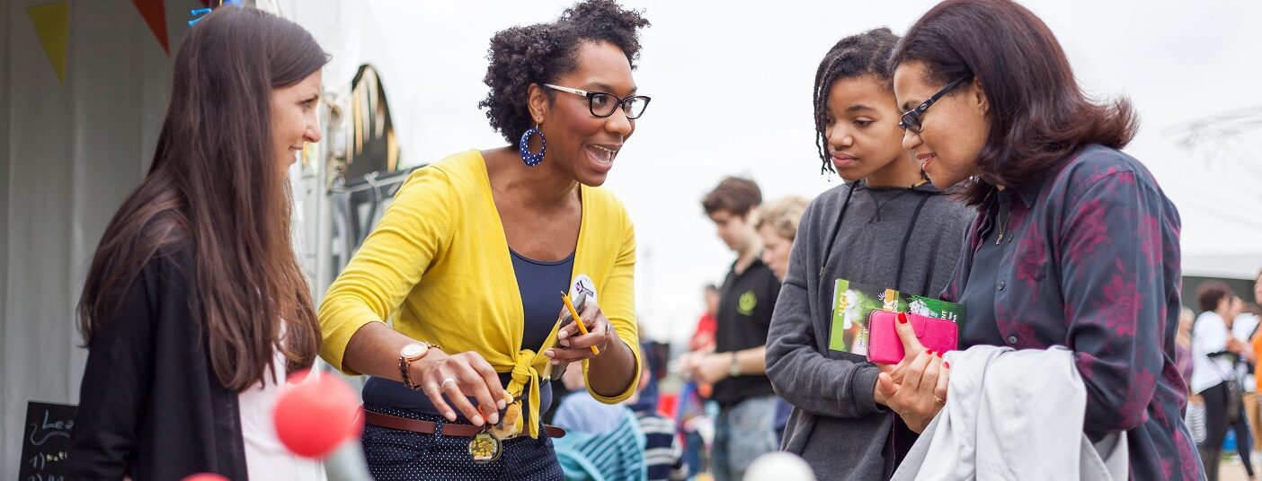 Four women discuss their work around a table of scientific paraphernalia.