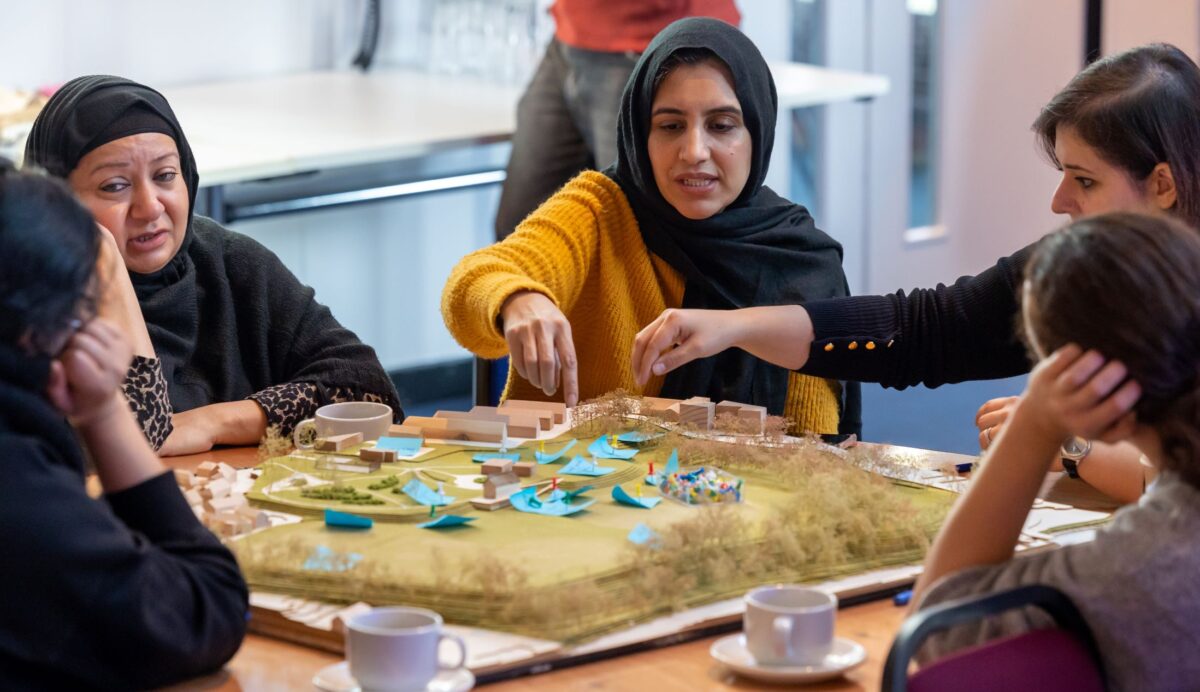Community members gather sit around a table with a model of green spaces