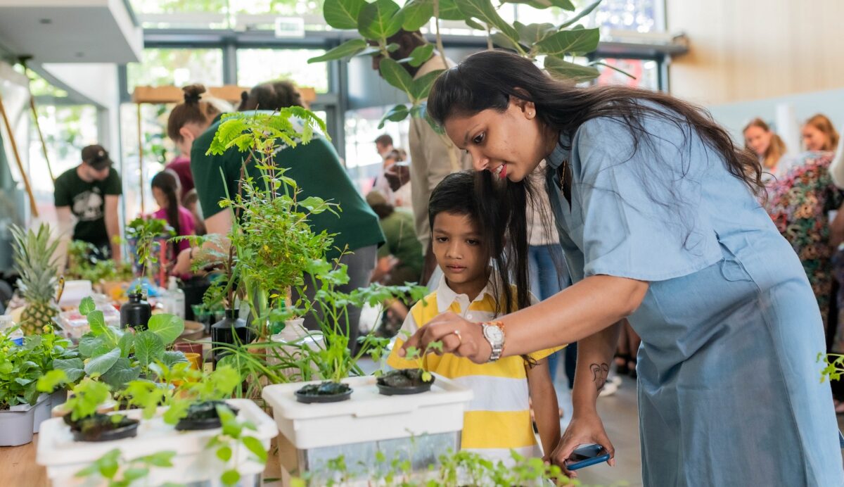An adult and young person lean over a table full of plants