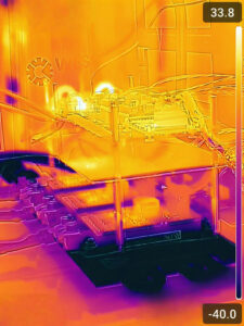 The image is taken by a thermal camera to show the temperature distribution of a power electronic device, with temperature values ranging from low temperature (black/blue areas) to room temperature (yellow/white areas). The cold plate at the bottom, appearing dark due to extreme cooling with liquid nitrogen (-173°C), absorbs heat from the power electronics, which appear in warmer colours. 