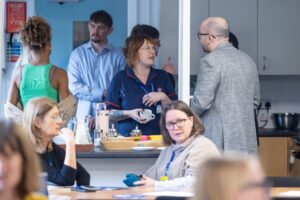 Attendees chat animatedly as they make cups of tea and coffee