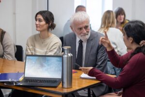 Three people are sitting around a table discussing the training session they are in