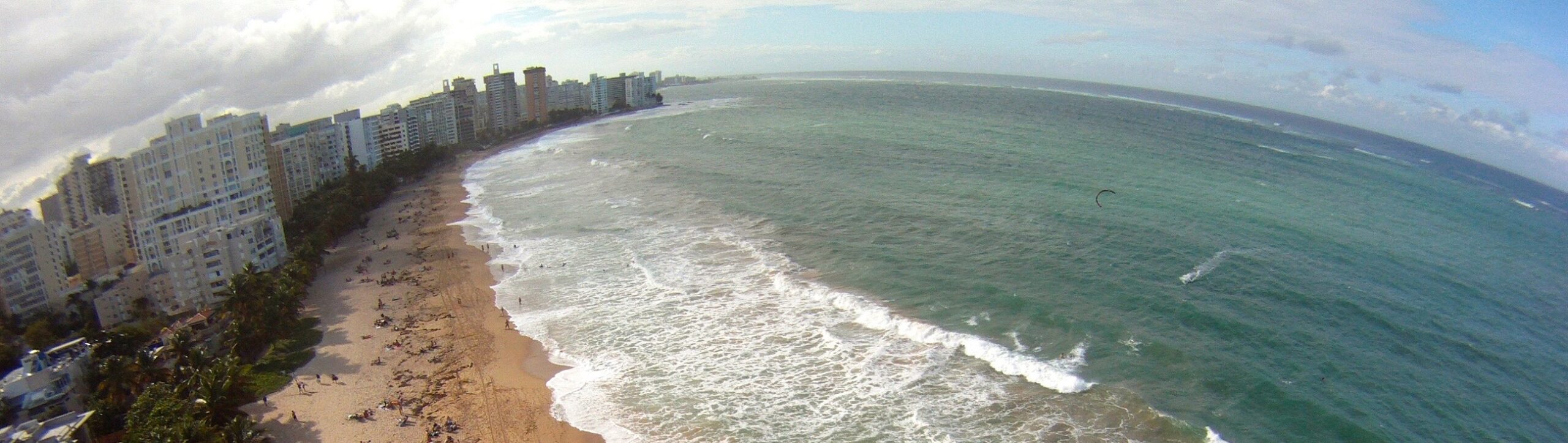 A picture of a coastal beach and town, distorted by a wide-angle lens.