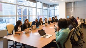 a group of people sitting around a table with laptops in front of them and engaging in some discussions