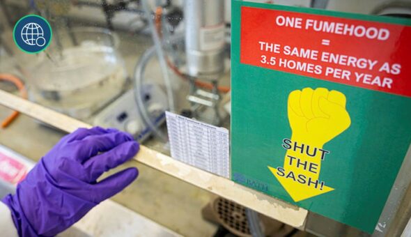 Gloved hand closes a fume cupboard with a sustainability sign on it