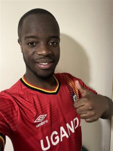 A smiling Jamaine giving a thumbs up in his Uganda football shirt.