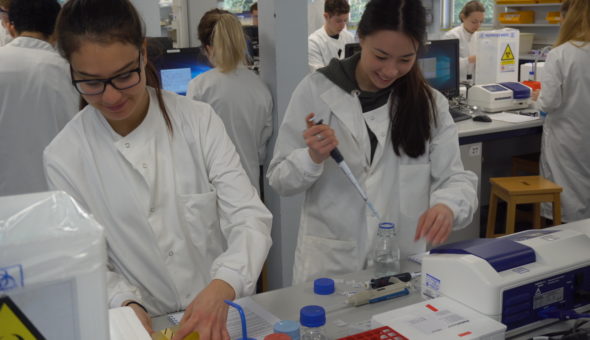Two female students in white lab coats experimenting in a laboratory