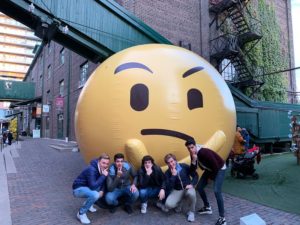 Five students stand with a giant inflatable emoji